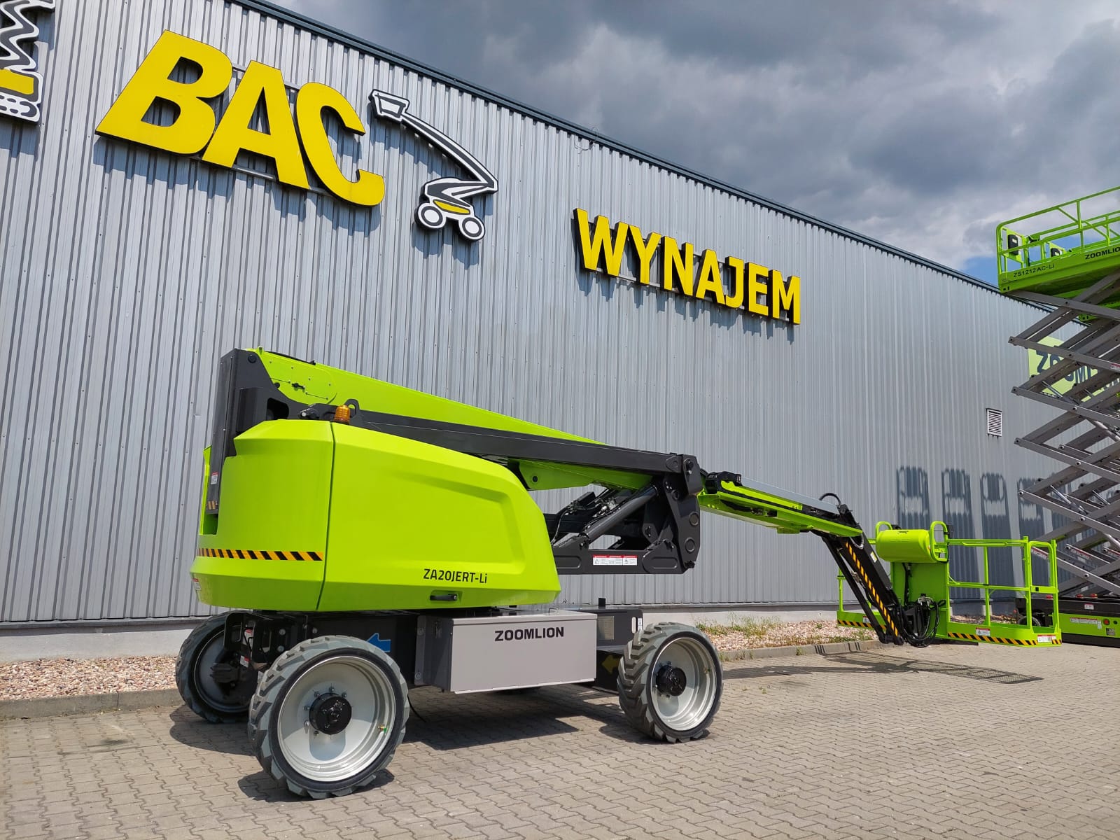 Podnośnik koszowy Zoomlion przed budynkiem BAC Wynajem.