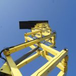 Žltý žeriav na modrej oblohe.