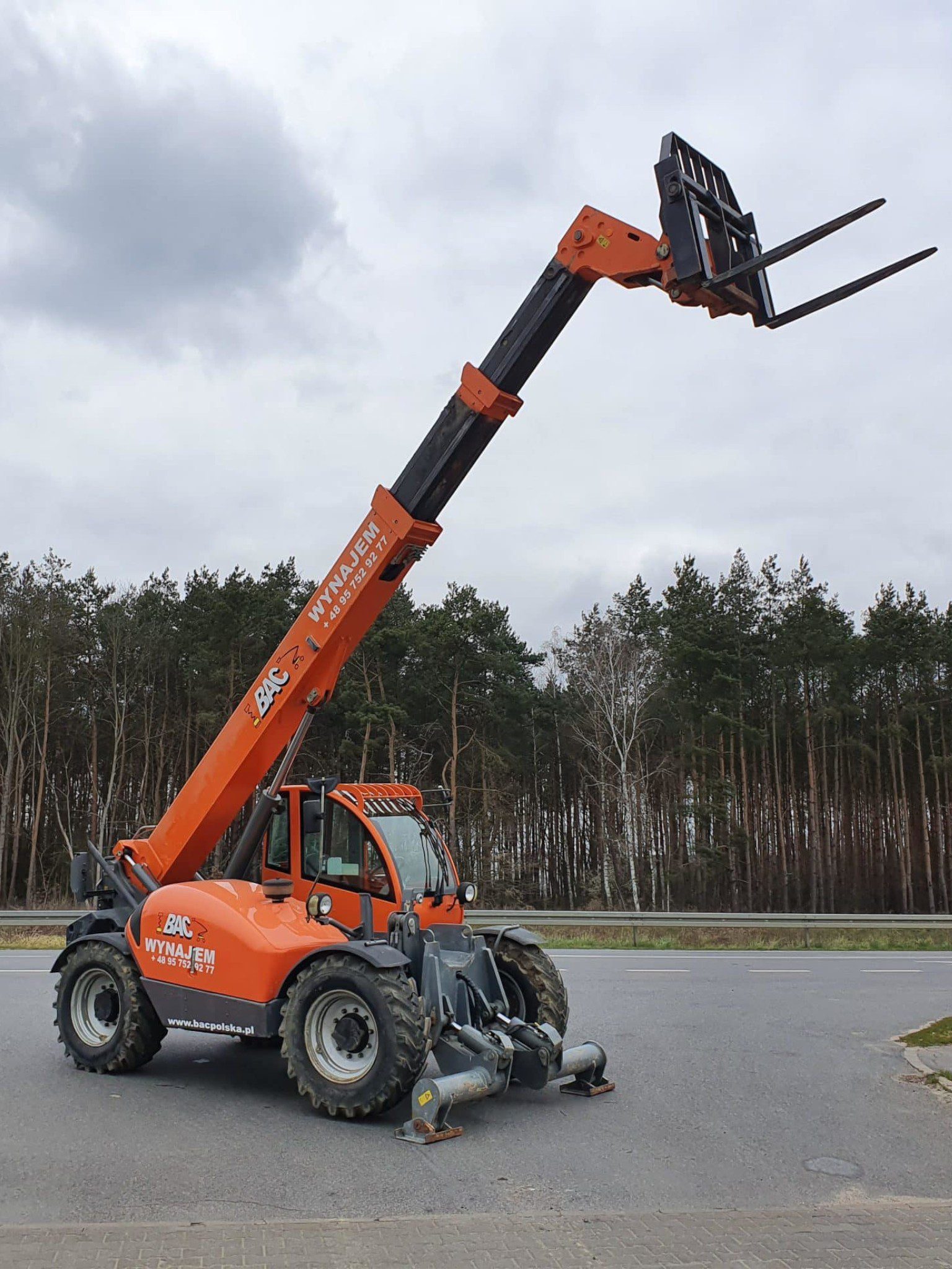Orange telescopic loader by a forest road
