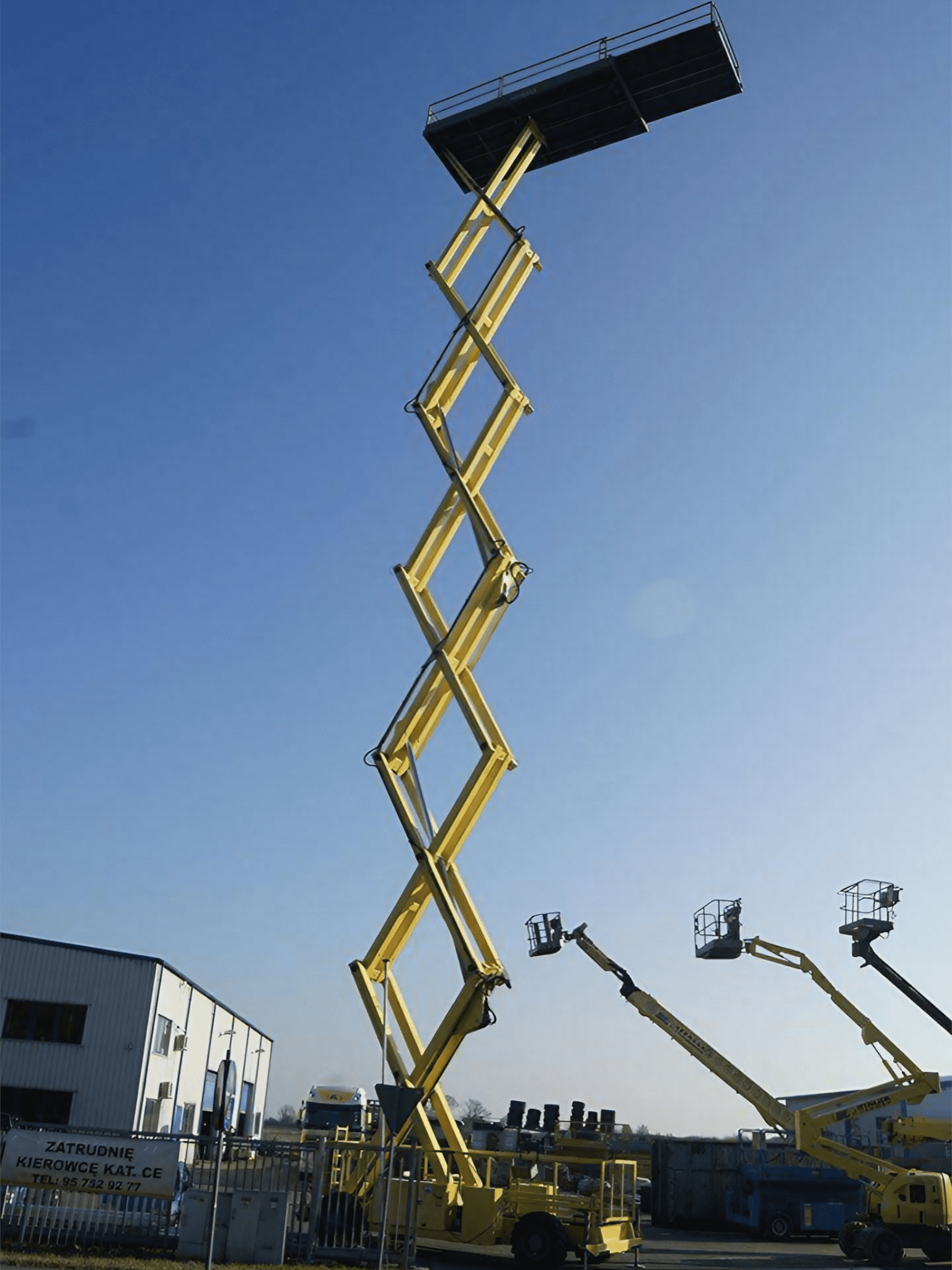 Żółty podnośnik koszowy na zewnątrz.