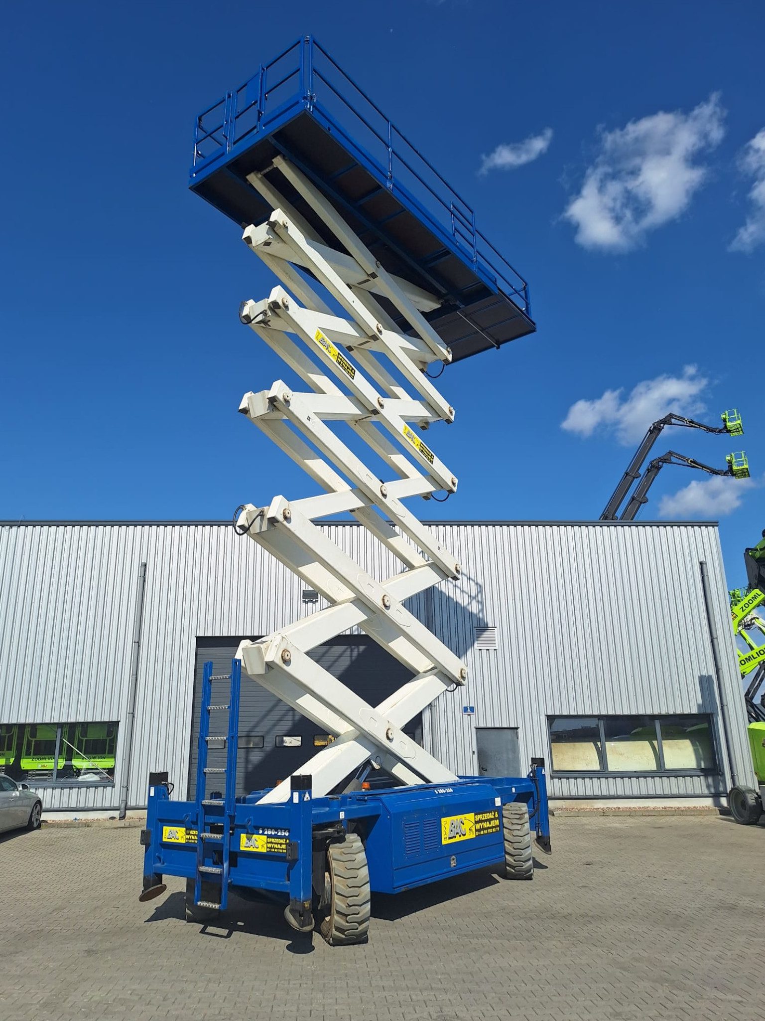 Elektryczny podnośnik nożycowy AB Lift S280-25 E4WDS o wysokości roboczej 28 metrów, wynajem w Bac Polska, zwyżka z białymi niebrudzącymi kołami i kompaktową konstrukcją