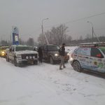 Samochody rajdowe w zimowym krajobrazie przy stacji paliw.