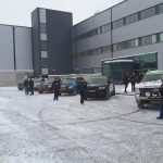 Osoby i terenowe samochody na zimowym parkingu.