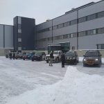 Parken vor dem Bürogebäude im Winter, Menschen und Autos.