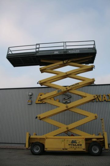 Scissor lift in front of an industrial building.