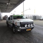 Pickup truck with advertisements standing in front of the warehouse.