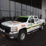 A white off-road vehicle with advertisements in front of the building.