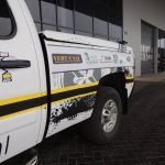 Company car with logo and advertisements in front of the building.