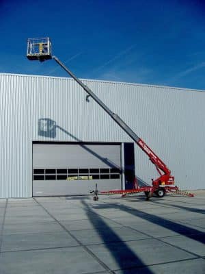 A basket lift in front of an industrial hall.