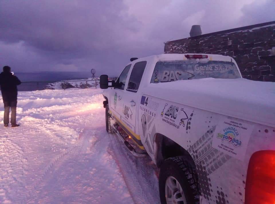 An off-road vehicle on a snowy road at dusk.