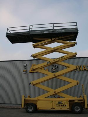 Yellow scissor lift in front of the warehouse building.