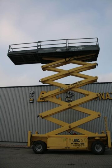 Yellow scissor lift in front of the warehouse building.