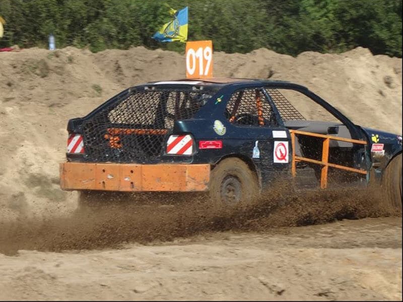 A rally car drifts on a dirt track.