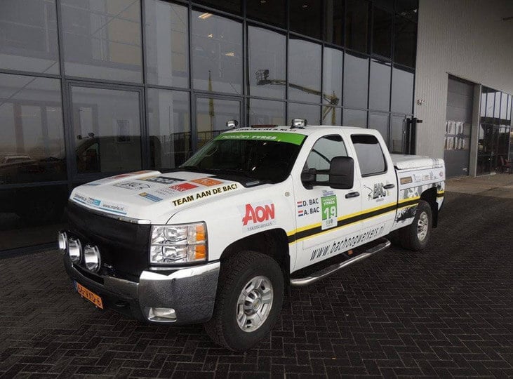 An off-road vehicle with an advertising wrapper in front of the building.