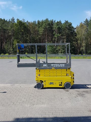 BAC scissor lift in the parking lot next to the forest.