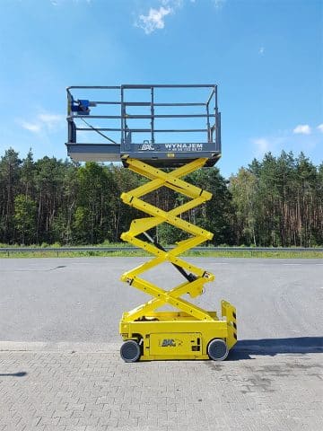 Żółta podnośnikowa platforma samojezdna na parkingu.