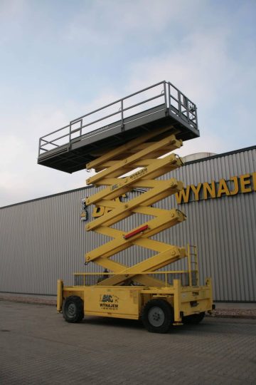 Yellow scissor lift in front of the building with the sign "RENTAL".