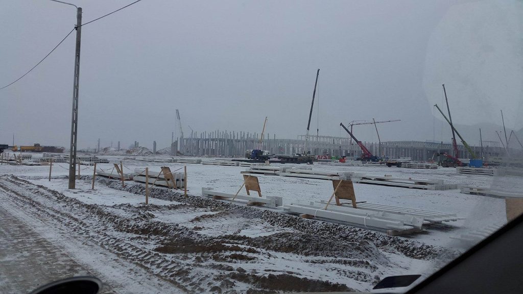 Stavba stadionu v zimě, jeřáby, sníh.