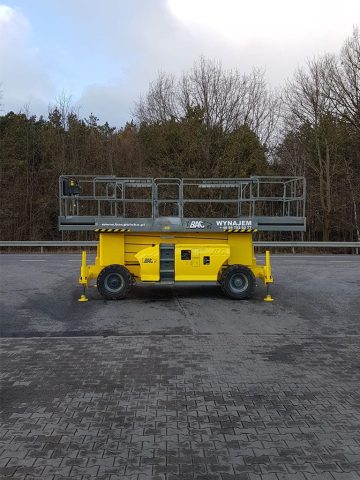 Żółta podnośnikowa platforma robocza stojąca na bruku.