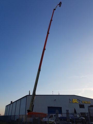 A crane in front of an industrial building at sunset.