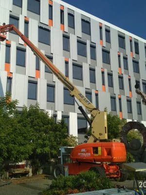 An aerial lift at work on the facade of a building.