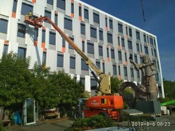 An aerial lift at work on the facade of a building.