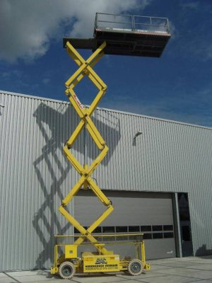 Scissor lift in front of an industrial building.