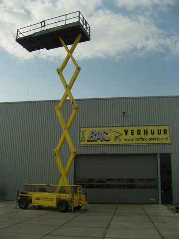 Scissor lift in front of an industrial building.