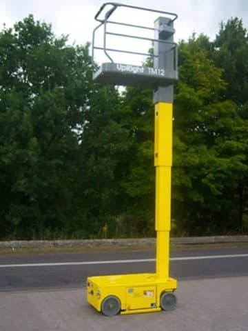 Upright TM12 yellow scissor lift on asphalt.