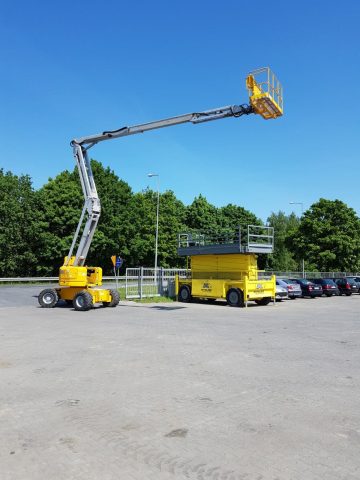 Żółty podnośnik koszowy na parkingu.