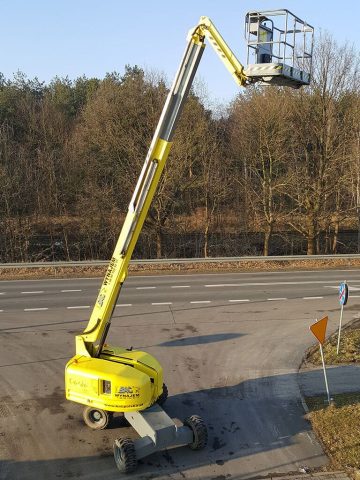 A basket lift by the road and trees.