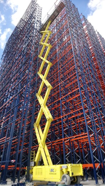 Yellow lift platform in front of metal scaffolding.