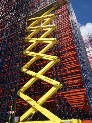A scissor lift next to a scaffold at a construction site.