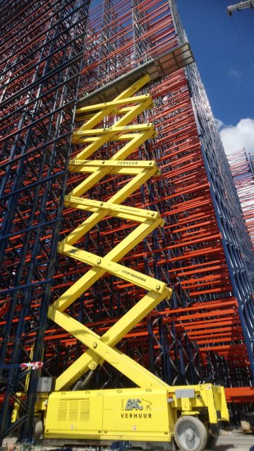 A scissor lift next to a scaffold at a construction site.