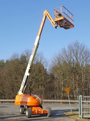 An aerial lift at a construction site next to a road.