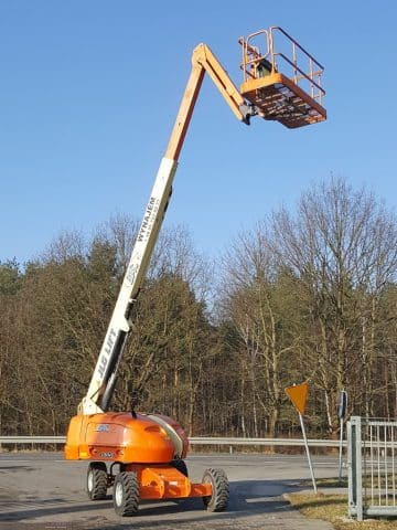 Podnośnik koszowy na budowie obok drogi.