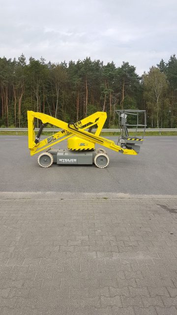 Scissor lift in a parking lot near the forest.