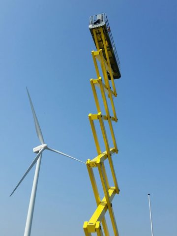 Żółta wieża serwisowa i turbina wiatrowa.