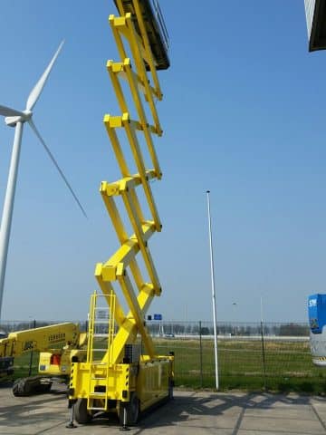 Żółta podnośnikowa platforma robocza przy turbinie wiatrowej.