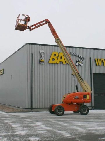 A basket lift in front of an industrial building.