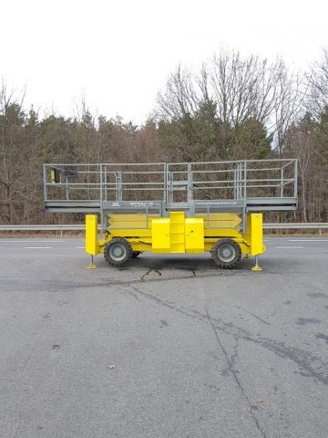 Żółta podnośnikowa platforma robocza na parkingu.