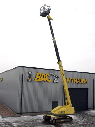 An aerial lift in front of a warehouse with a sign reading "Rental."