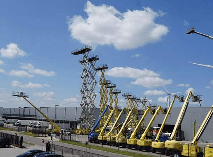 Aerial work platforms by the warehouse, blue sky.