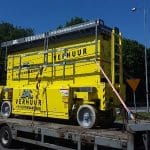 Gelbe mobile Toilette auf einem Lastwagenanhänger.
