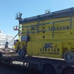 A truck carrying a yellow jack and construction materials.