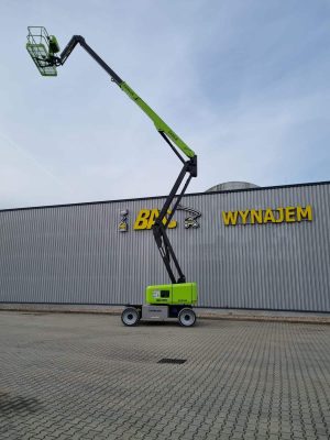 Podnośnik koszowy Zoomlion przed budynkiem z napisem "Wynajem".