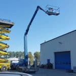 A yellow scissor lift and a blue lift by the warehouse.