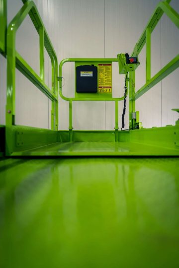 Green industrial platform with handrails and control panels.