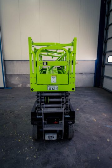 Green scissor lift in the industrial hall.