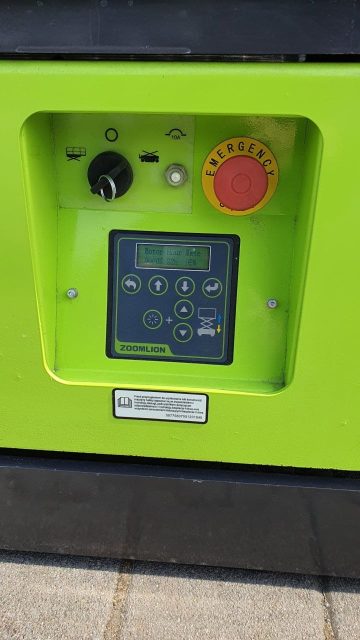 Zelená ovládací deska stroje s nouzovým tlačítkem.